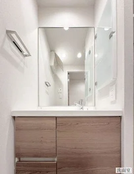 白い洗面台と大きな鏡、木製の収納棚がある洗面所の interior.