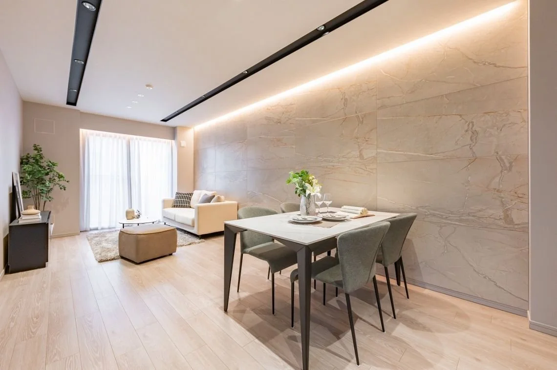 リビングルームとダイニングルームがつながった現代的なインテリアのリビングスペース。ソファ、テーブル、ダイニングテーブル、椅子、観葉植物などの家具と装飾品が置かれている。