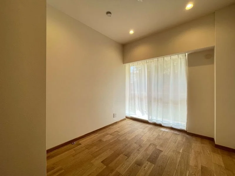 明るい窓のある空の部屋、木製のフローリングと白い壁.