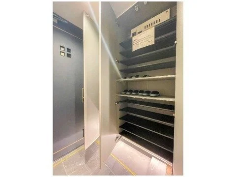 靴のシューズラックと電気配電盤が設置された室内の画像