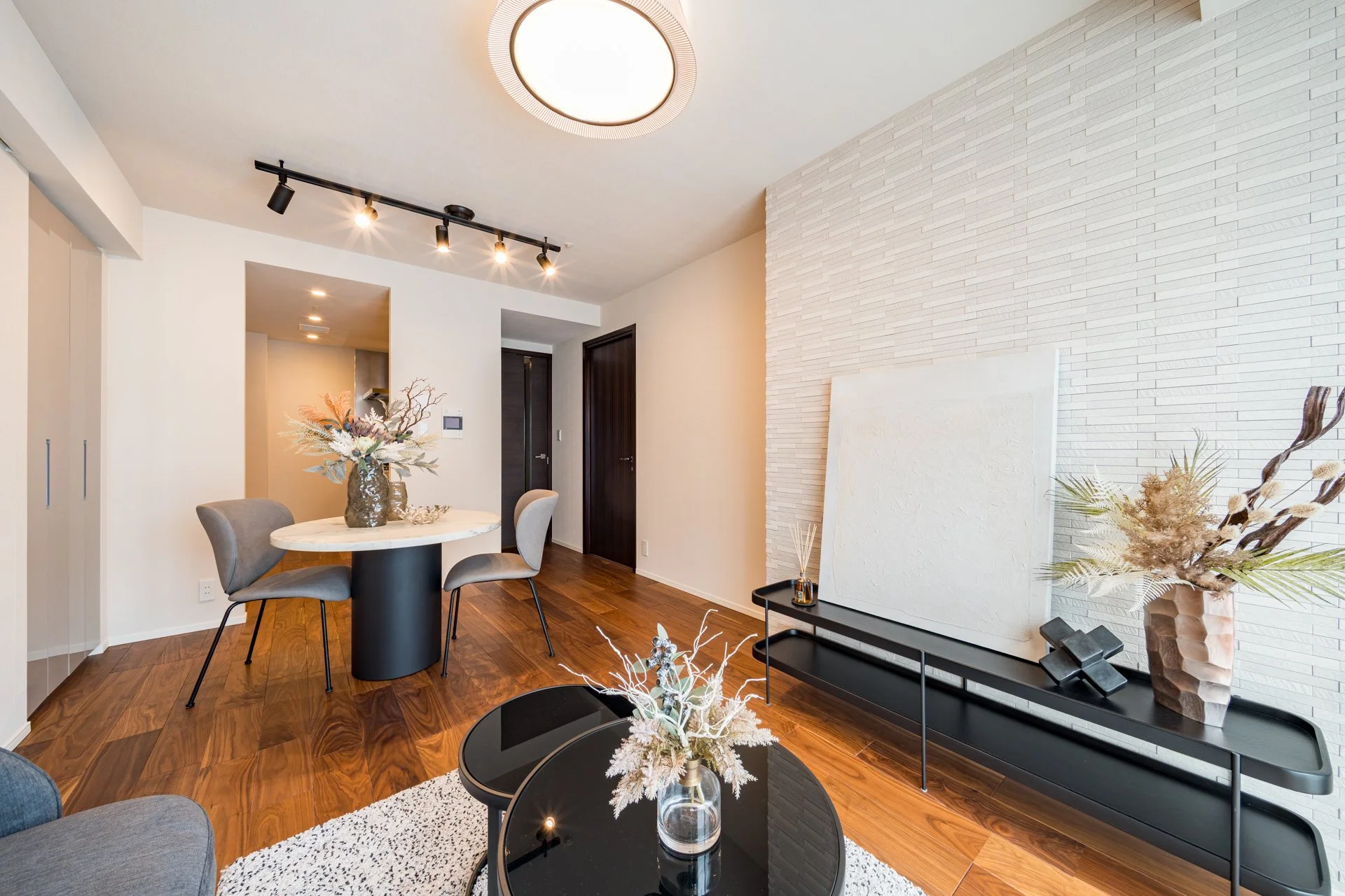 モダンなリビングルームとダイニングエリアのインテリア。木製床とホワイトの壁、観葉植物と装飾品が配置されている。