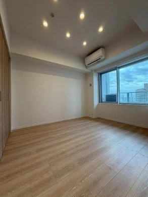 空の部屋、木の床、天井には回折灯、エアコンと大きな窓付き