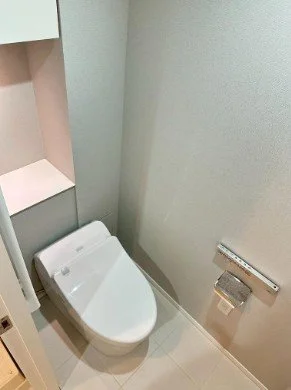 トイレとトイレットペーパーのホルダーが壁に取り付けられたトイレルームの内部の写真