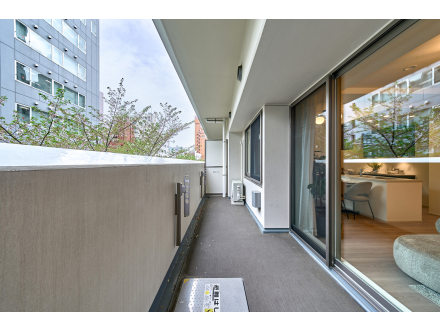 都市のマンションのバルコニーからの眺めと室内の様子が見える。