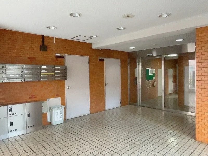 集合郵便箱、ゴミ箱、エレベーターがある建物のロビーの内側