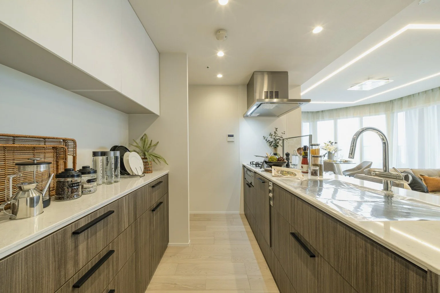 モダンなキッチンとダイニングエリア、白いカウンターと木製キャビネット、調理器具や装飾品が配置されている家の内装