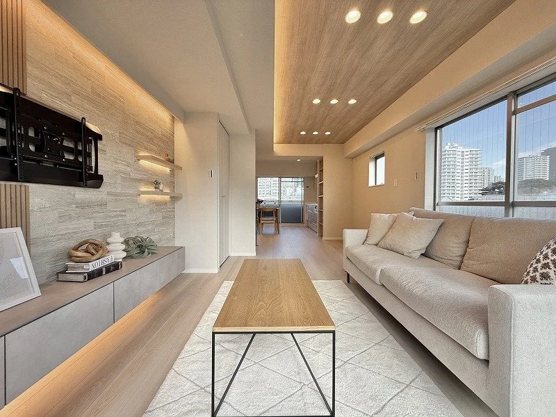 明るいリビングルーム。ソファ、コーヒーテーブル、大型窓から都市の景色。