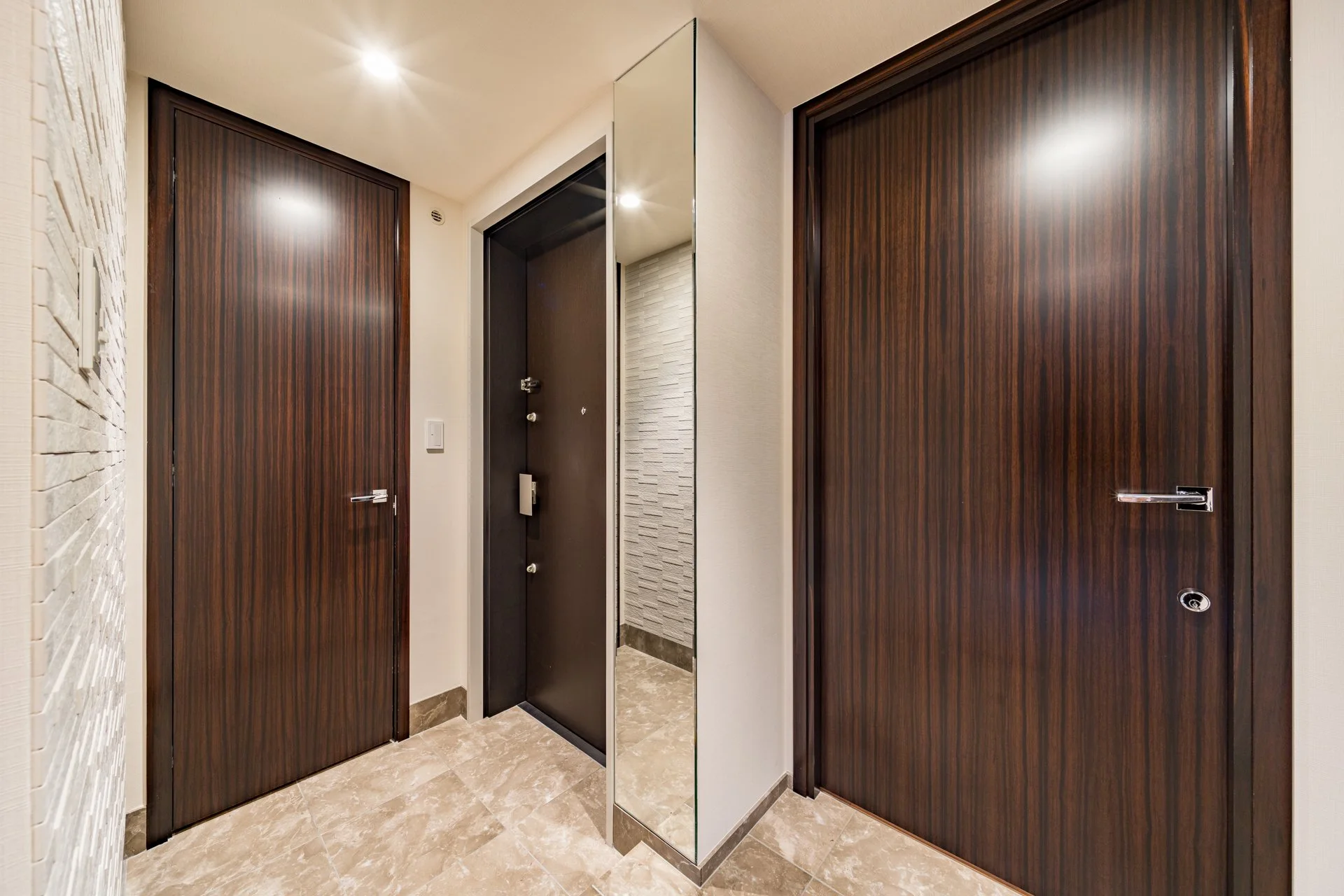 エレベーターの前の廊下、木製の扉と鏡が設置された待合スペース。