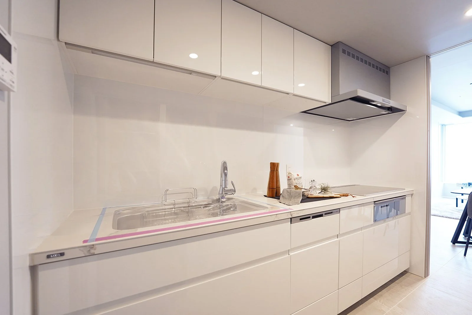 白いキッチンのシンプルなカウンターと収納棚。調理器具や飾りが置かれている。