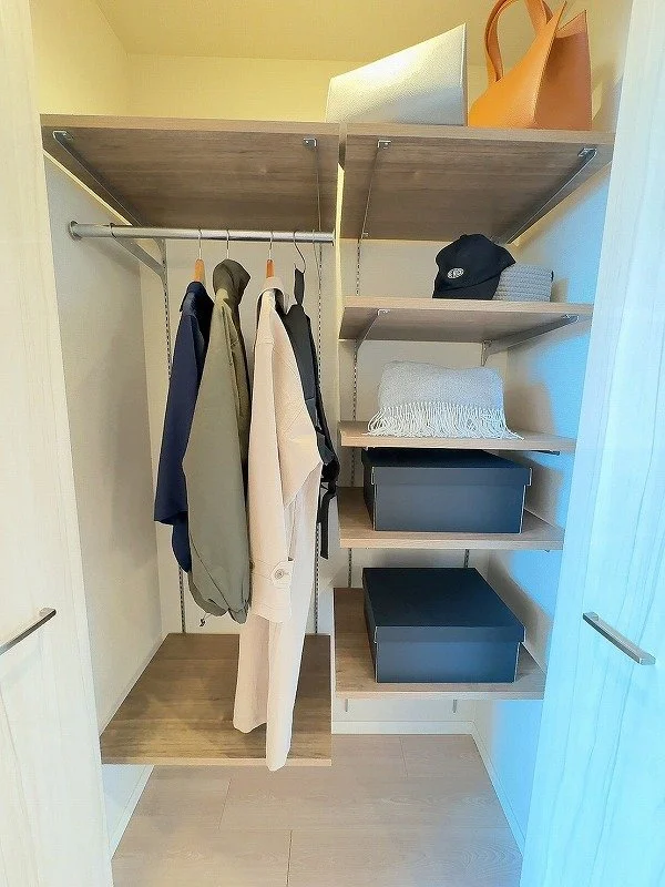 クローゼットの中にコートやジャケット、帽子、バッグ、収納ボックスがあります。