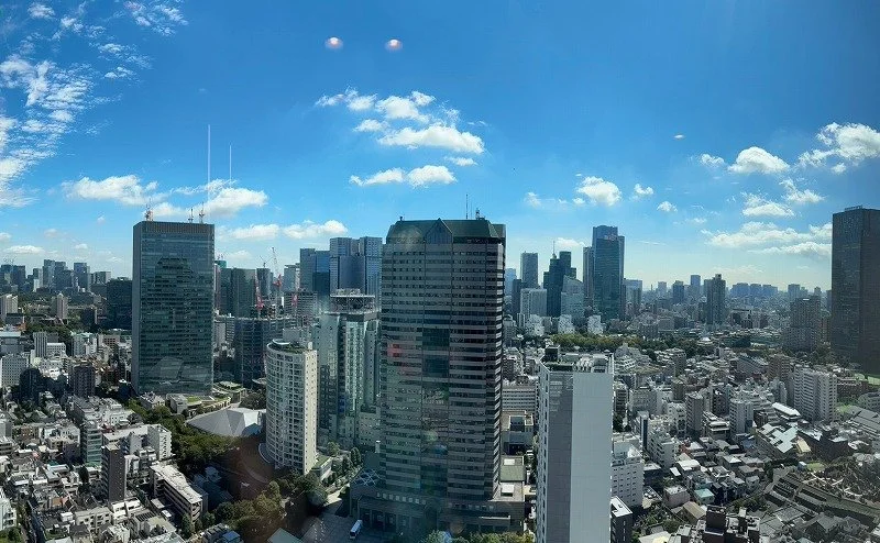 高層ビルが立ち並ぶ都市のスカイラインと青空、雲と太陽が映る都市の景色