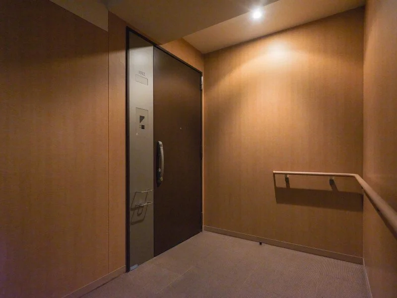ホテルのエレベーターホール、木目調の壁と手すりがある。