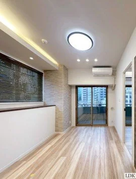 明るいリビングルーム、木製の床、天井と壁に設置された照明、窓から都市の景色、エアコンが設置された空間