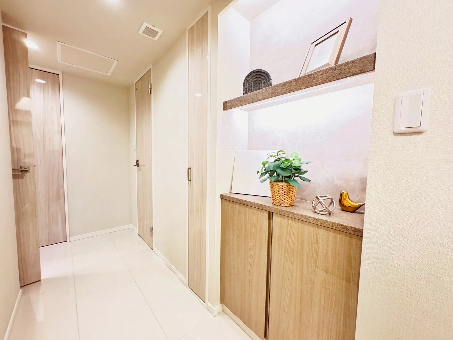 リビングの廊下にある飾り棚に植物と装飾品が置かれている風景。」}