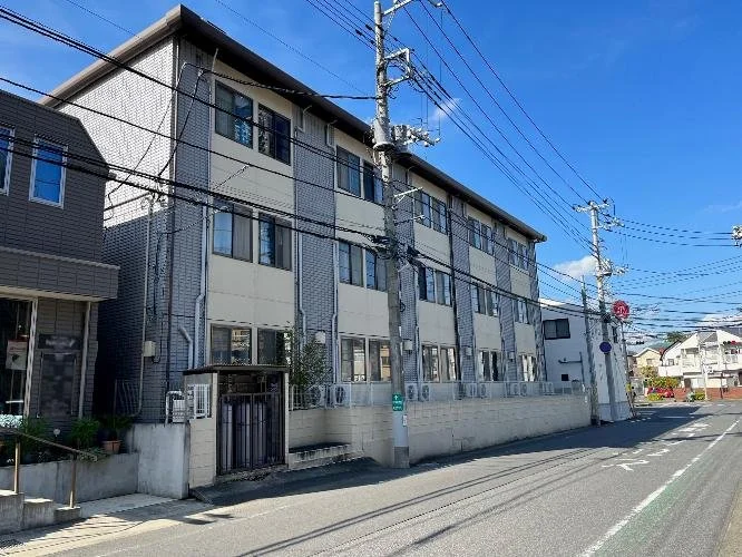 三階建ての住宅が並ぶ街並みと電柱、電線、青空