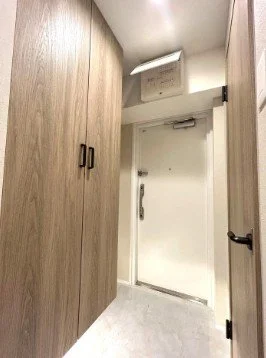 白いドアと木製の収納扉がある狭い廊下の内部。
