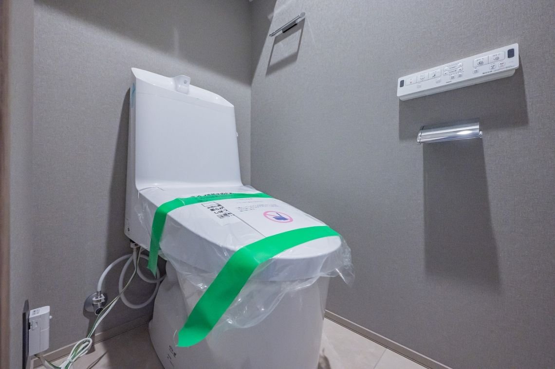 新しいビニールに覆われたトイレの便器と、それに取り付けられた操作パネル。