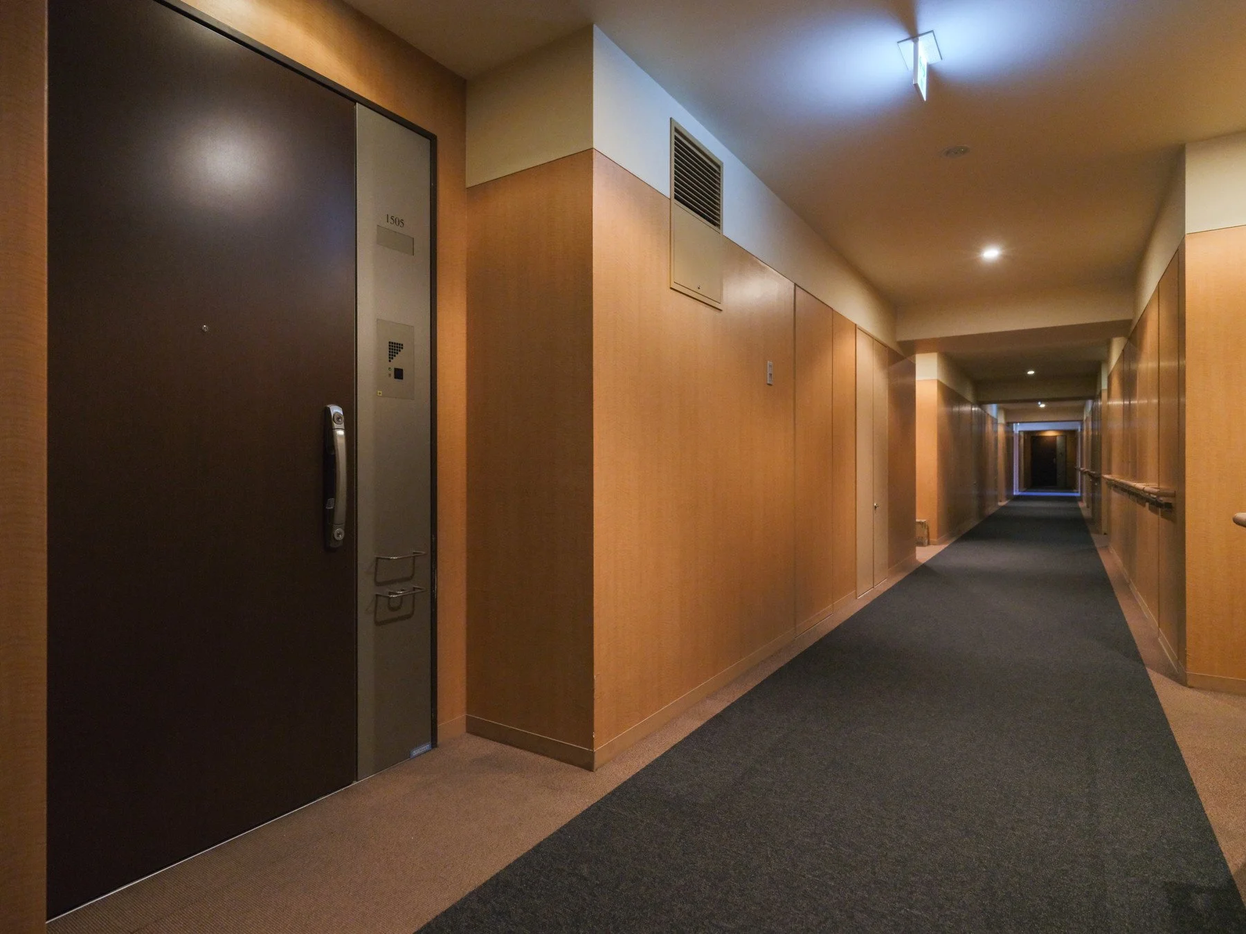 ホテルの廊下、木製の壁とカーペット敷きの通路、ドアが並んでいる