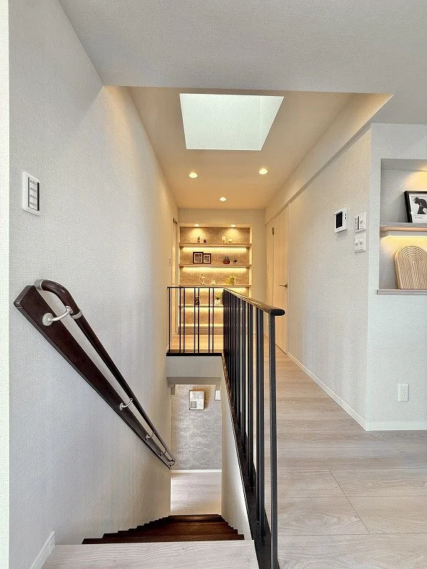 明るい廊下と階段、天窓と壁の飾り棚が見える interior of a modern home hallway