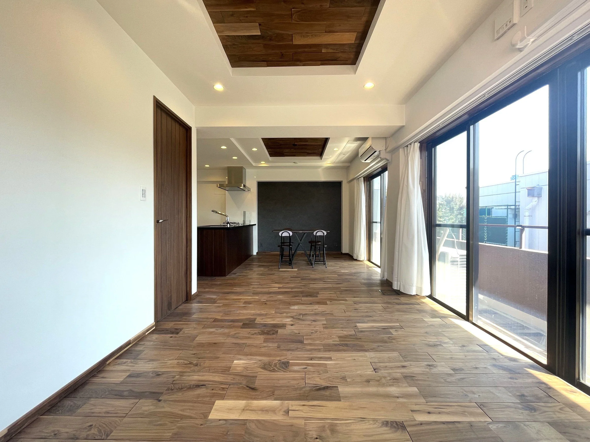 木目調の床と壁、大きな窓から自然光が入るリビングルームの interior.