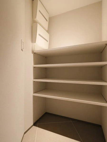 白い壁の棚と空の本棚がある部屋の角