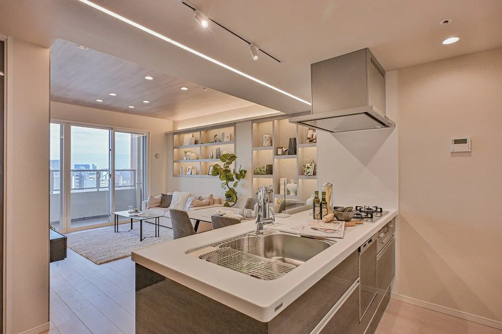 リビングルームとキッチンのオープンプランのインテリア。ソファとシェルフ、バルコニーの窓が見える明るい空間。