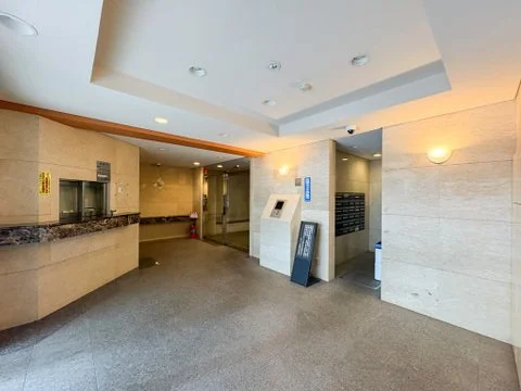 エレベーター前のロビーの interior, with a reception desk, mailboxes, and a keypad panel.