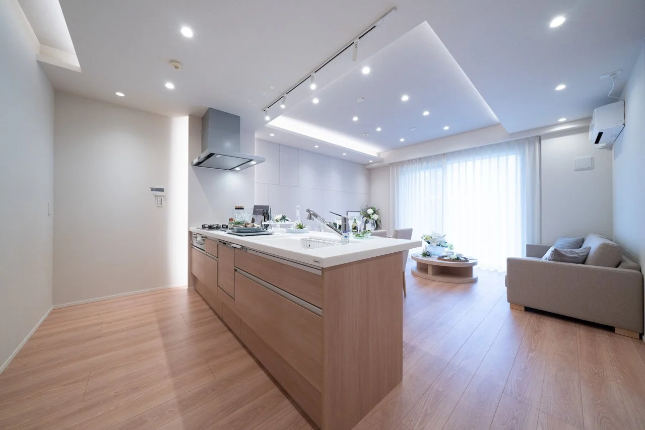 モダンなリビングルームとキッチンの居住空間、白い壁と木製の床、自然光が差し込むシーン
