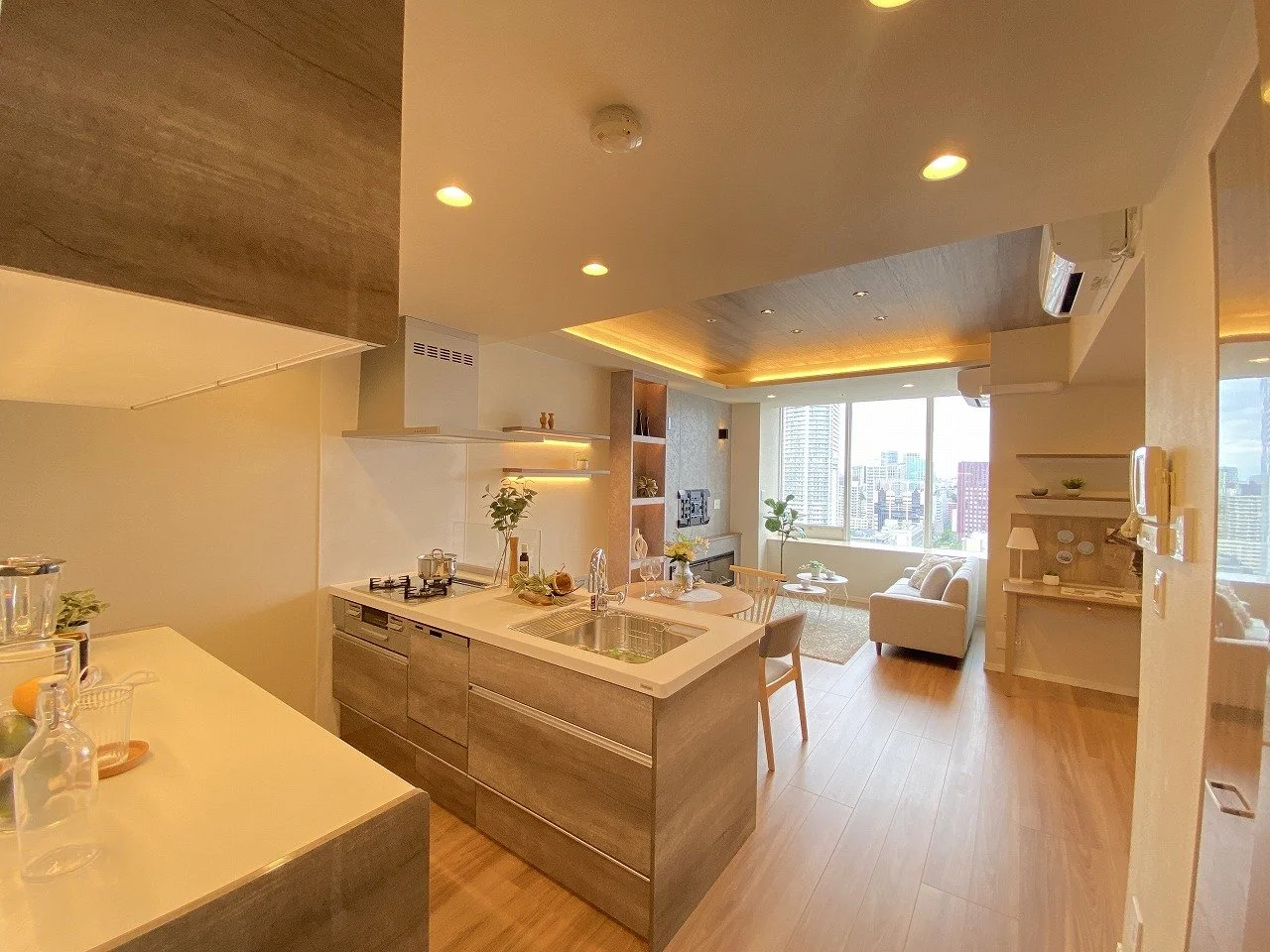 明るいリビングとキッチンのあるモダンなマンションの室内風景、木製の床と大きな窓から見える都市の景色
