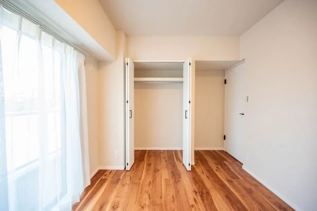 空のクローゼットと木製フローリングのある部屋の内部