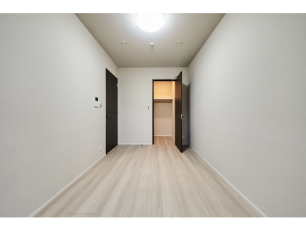 空の部屋、木の床、白い壁、天井に照明付きのシーリングライト、ドアが開いてクローゼット棚が見える