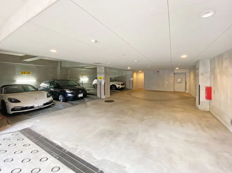 車が停まっている地下駐車場の内部。白や黒の車が数台見える。