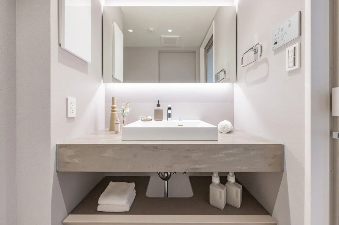 白い洗面台と鏡、シンプルなバスルームの洗面エリア