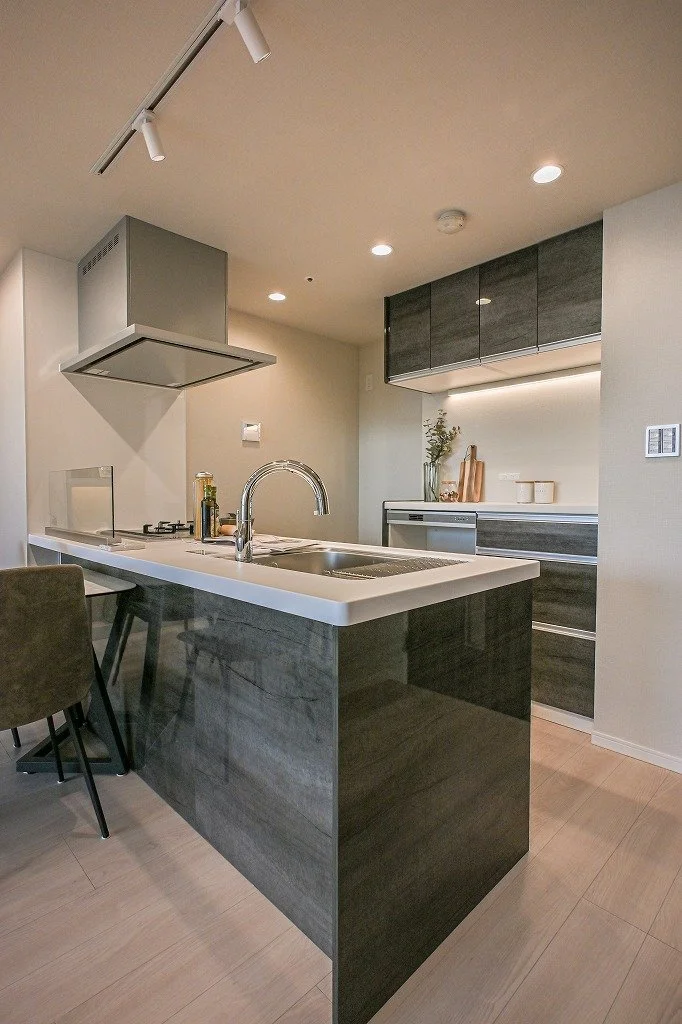 モダンなキッチンの interior, 白いカウンターとダークな木製キャビネット, シンクとガスコンロ, 照明と飾り棚があります.