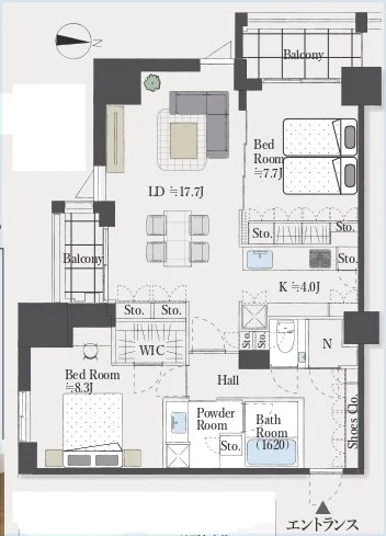 二つのバルコニー付きの住宅の間取り図。リビングダイニング（17.7畳）にはソファとダイニングテーブルが配置されている。寝室が二つあり、一つにはウォークインクローゼット（WIC)が付いている。キッチンは4畳で、バスルームとパウダールームが隣接している。玄関からホールと複数の収納スペースにつながる。