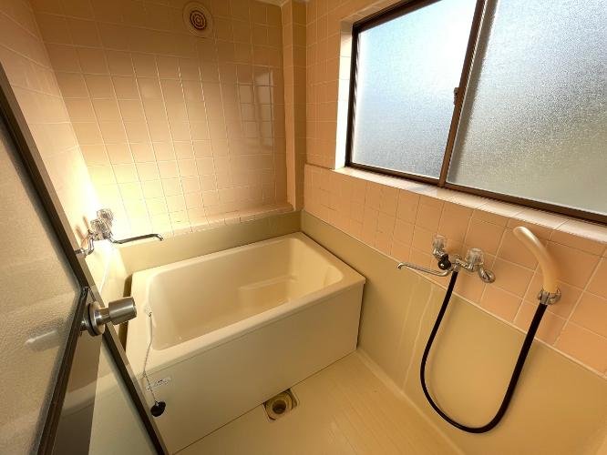 浴室のバスタブとシャワーヘッド、窓と壁のタイル