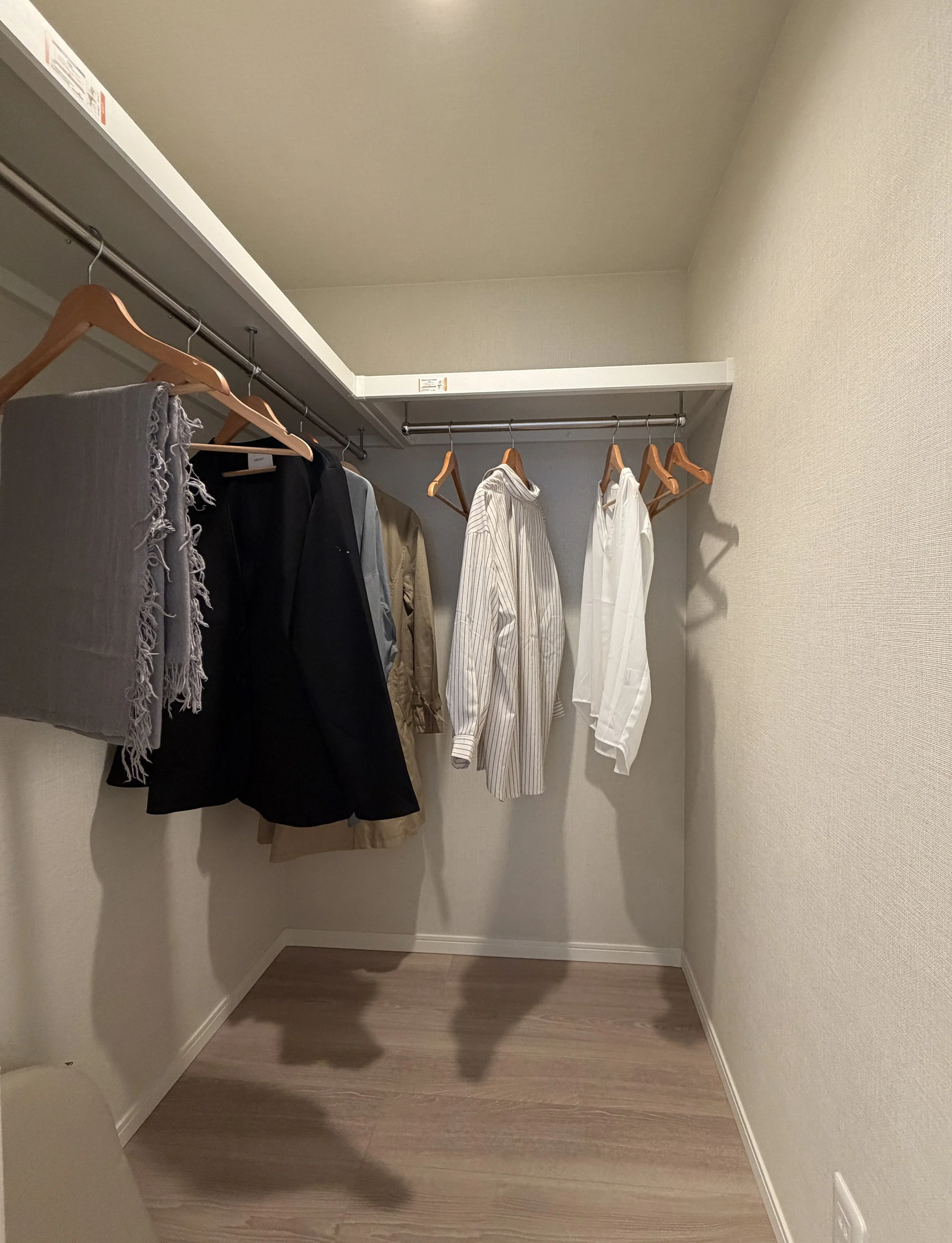 クローゼットの中にハンガーにかけられた服やブランケットが見える。