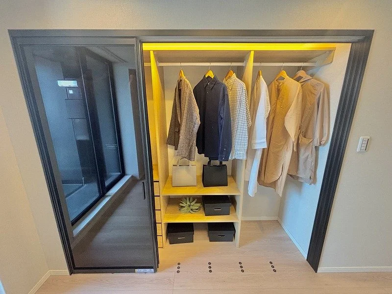 クローゼットにかかった服と収納ボックスの画像