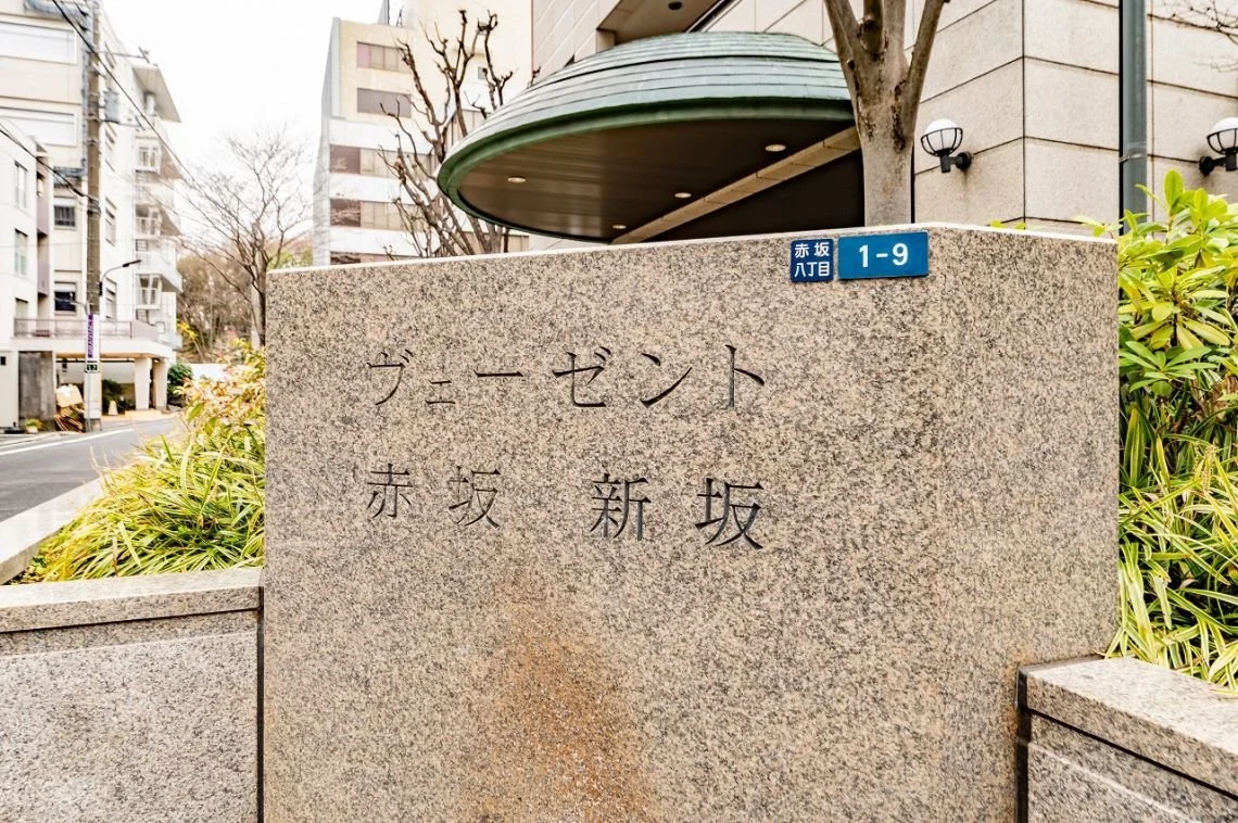 都名の碑とレタッチされた青い住所表示板が写っている。