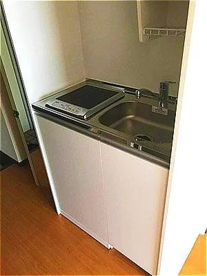 狭いキッチンにシンクとコンロ、棚があるシンプルな設計のキッチン。