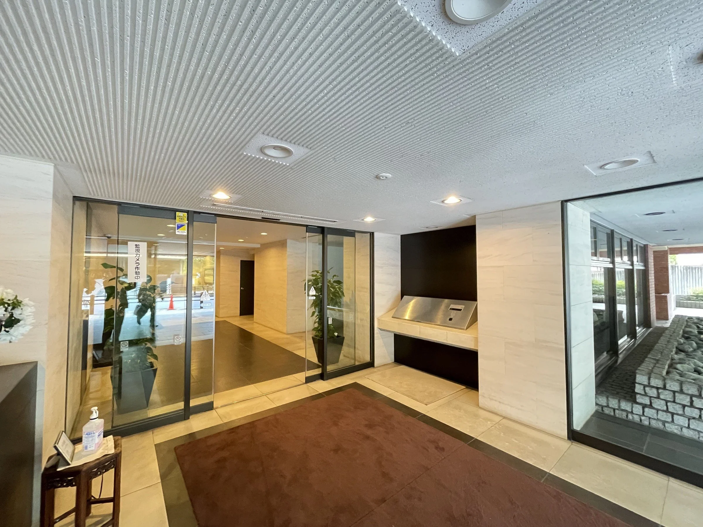 エントランスの内部の様子。ガラスのドアとビルのロビーの様子が見える。