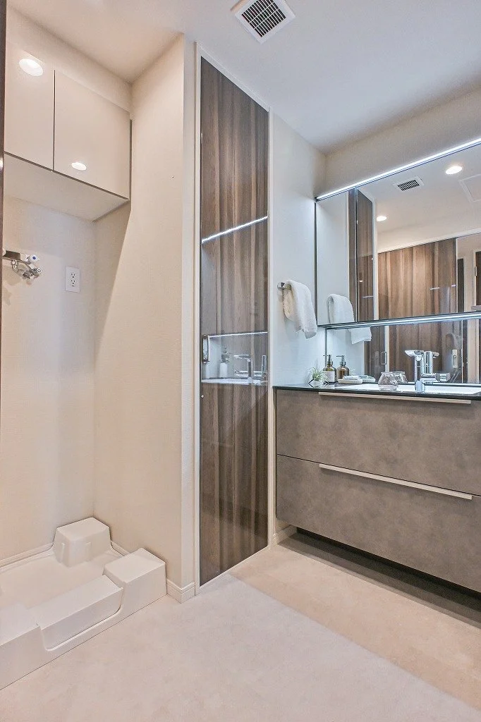 洗面台とミラー、タオル掛け、収納棚があるモダンなバスルームの一部です。