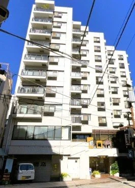 高層の白いマンション建物と駐車場入口の風景,青空