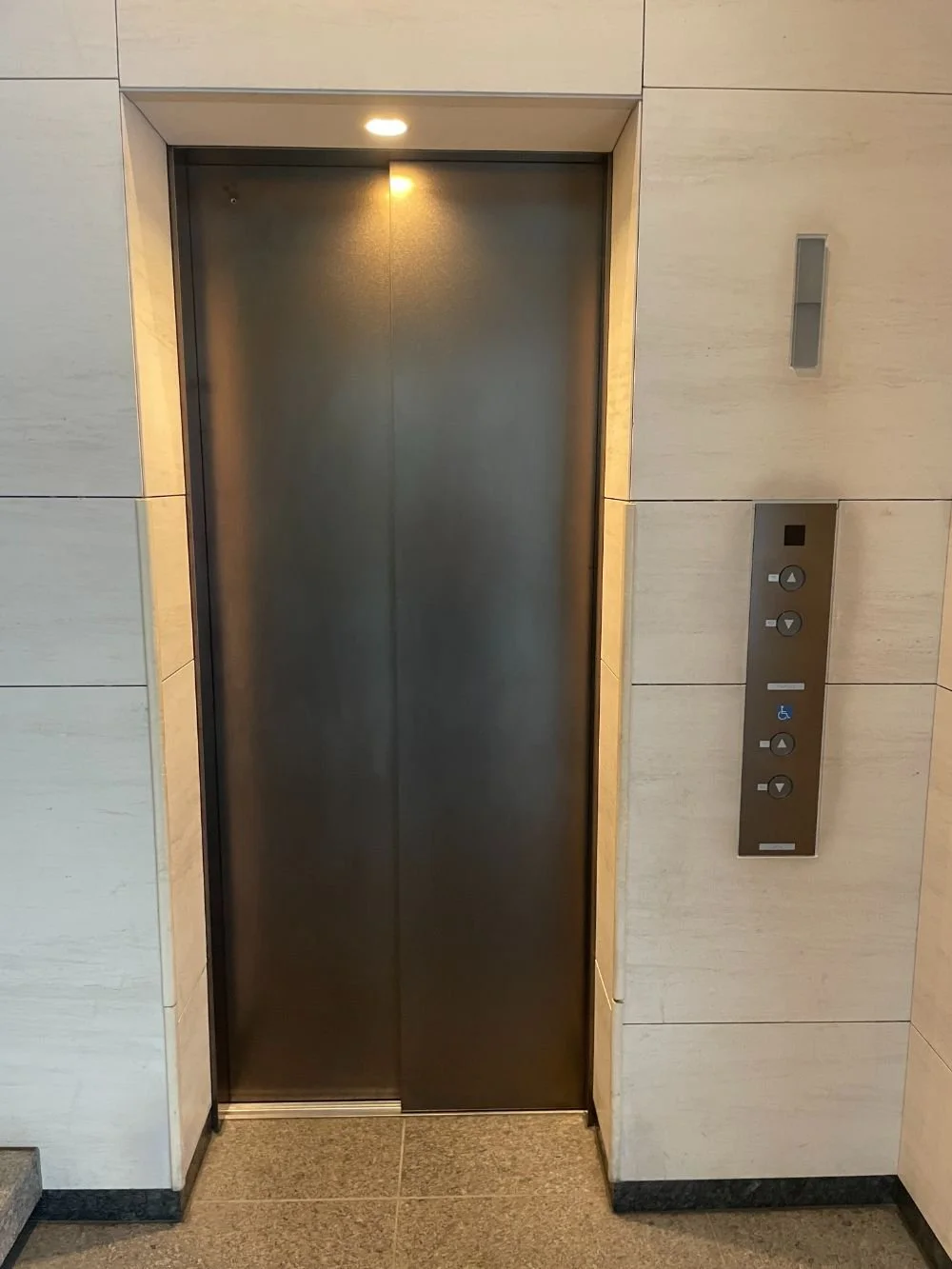 閉じたエレベーターの扉と操作パネルが壁に囲まれている。