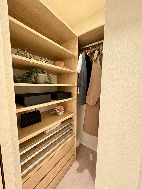 木製のウォークインクローゼットに衣服と装飾品が整然と収納されている