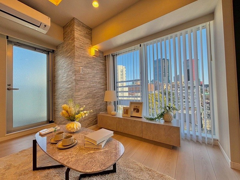 都市の景色が見えるリビングルームの大きな窓とカーテン、家具と装飾品が配置された内装