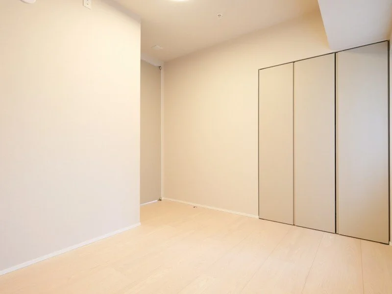 白い壁と白い床の空間、右側に折りたたみ式の収納扉が見える部屋