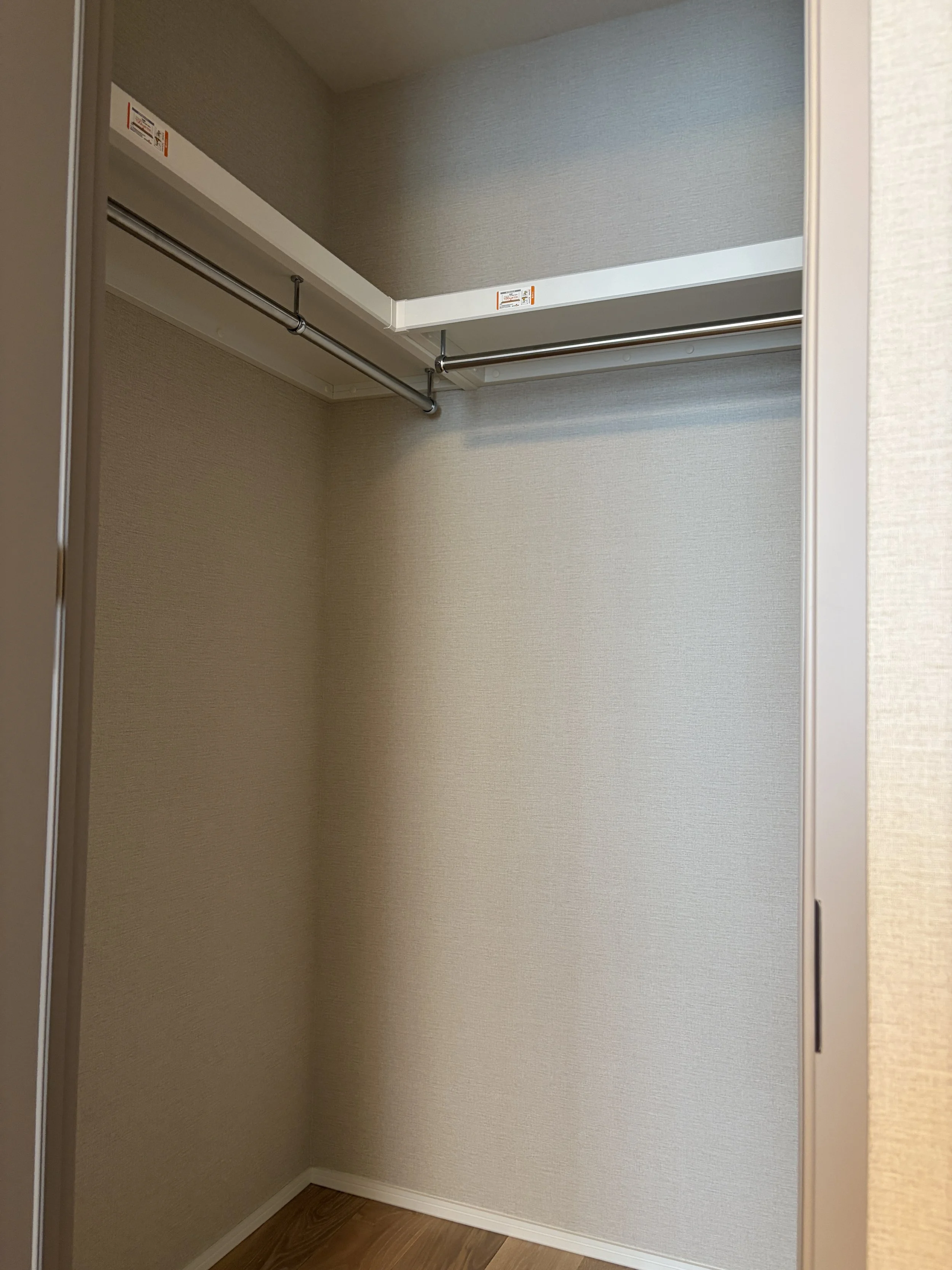 空のクローゼット内側、壁紙と木製の床が見える