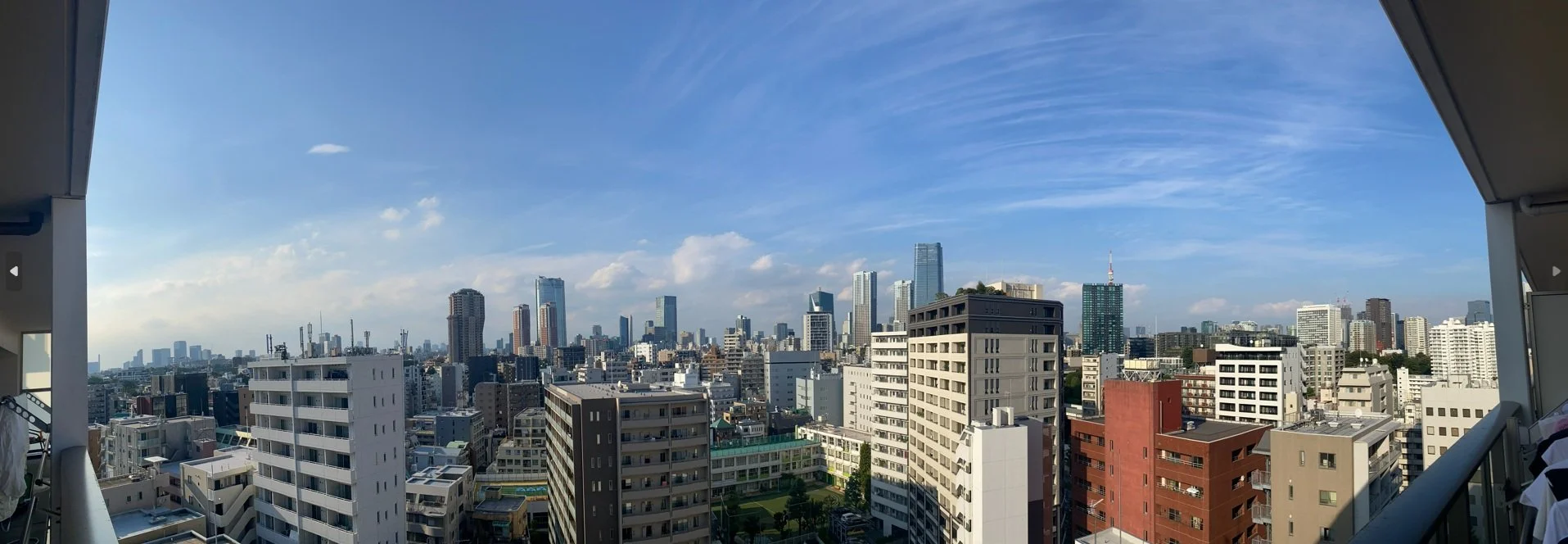 東京の高層ビル群を見渡せる都市の景色。青空と薄い雲が広がる日です。