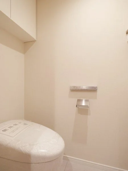 トイレの便座と壁に取り付けられた棚と紙巻き器